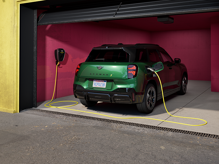 Den helelektriske MINI Aceman i British Racing Green som lader i en garasje, sett bakfra. 