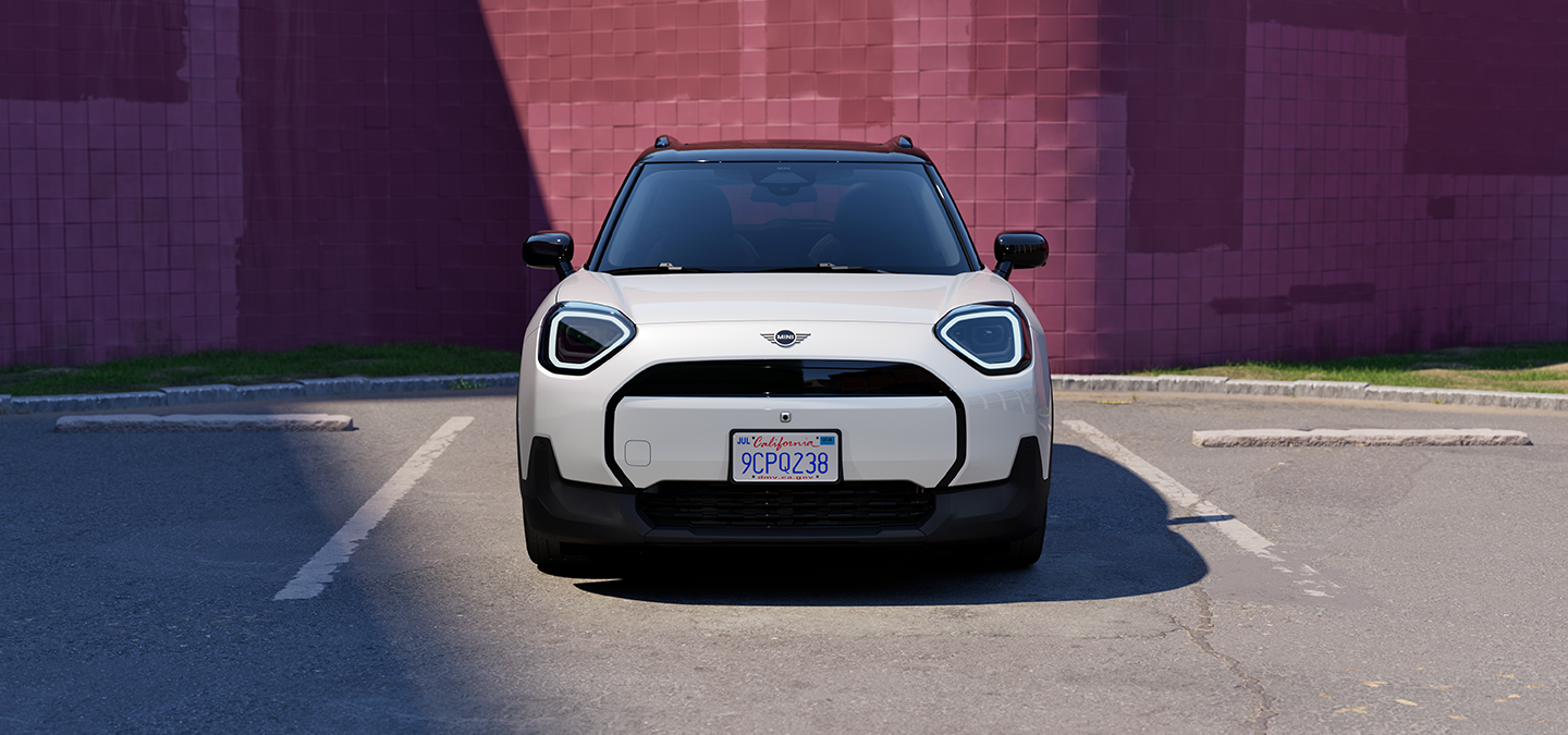 Den helelektriske MINI Aceman i Nanuq White og svart tak, som står parkert, sett forfra.