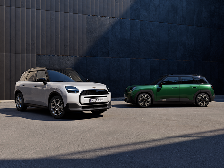 Den helelektriske MINI Aceman i Nanuq White og British Racing Green med svart tak i en gate sett forfra og fra siden.