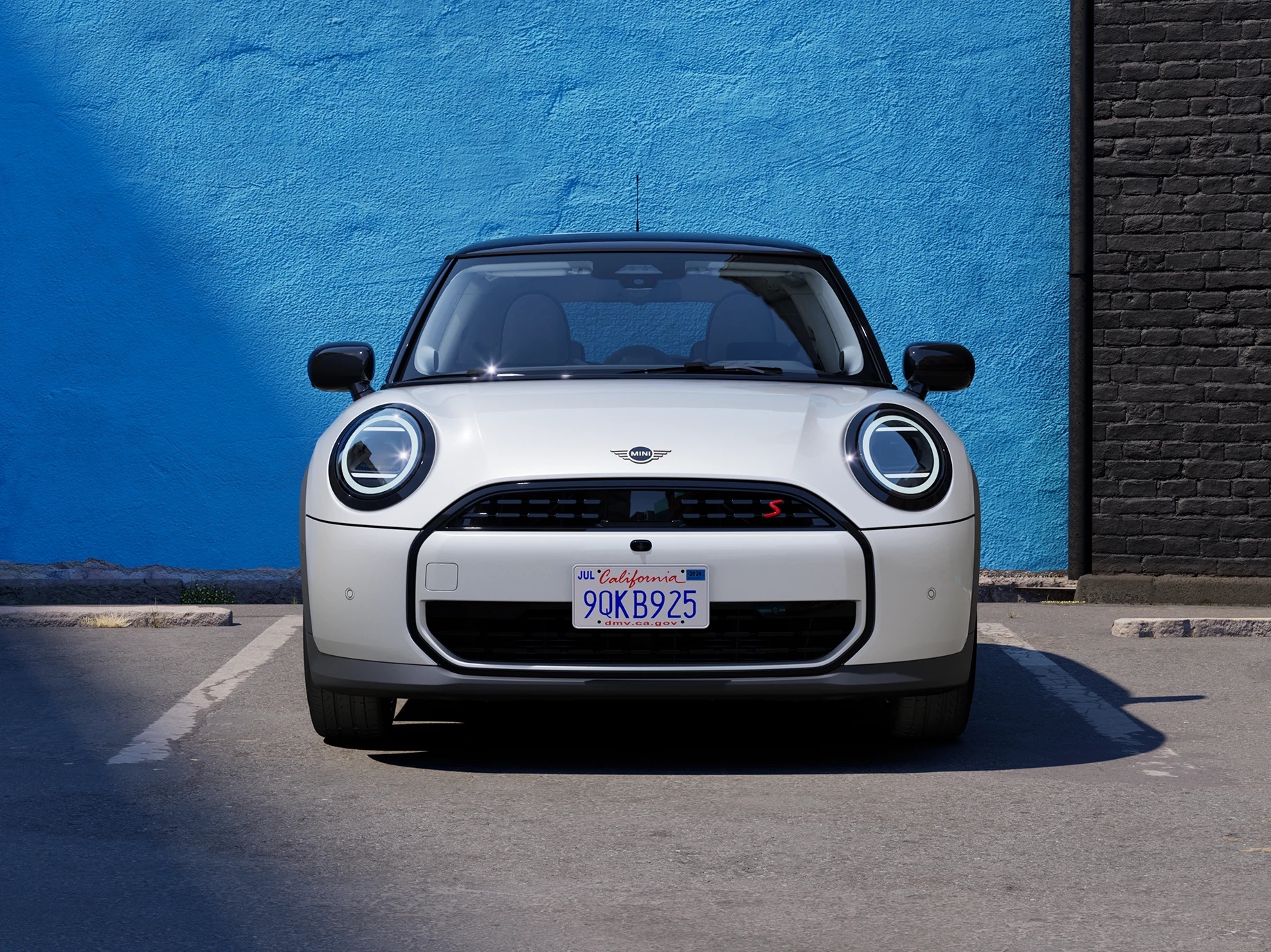 MINI Cooper i Nanuq White med svart tak som parkerer, sett forfra.