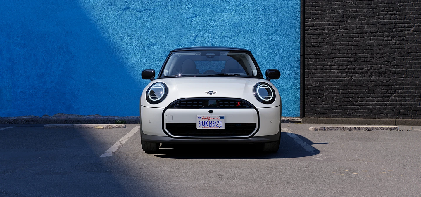 MINI Cooper i Nanuq White med svart tak som parkerer, sett forfra.