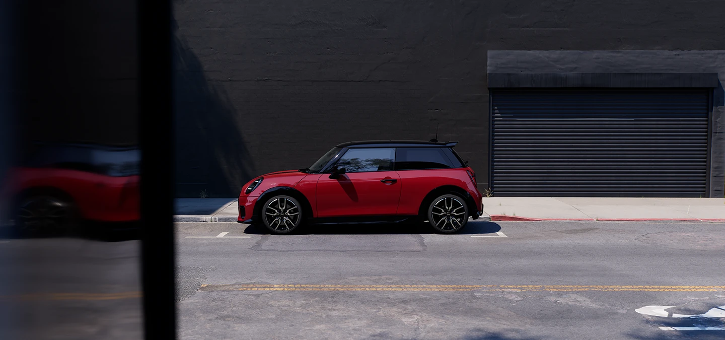 MINI Cooper i Chili Red med svart tak som parkerer, sett fra siden.
