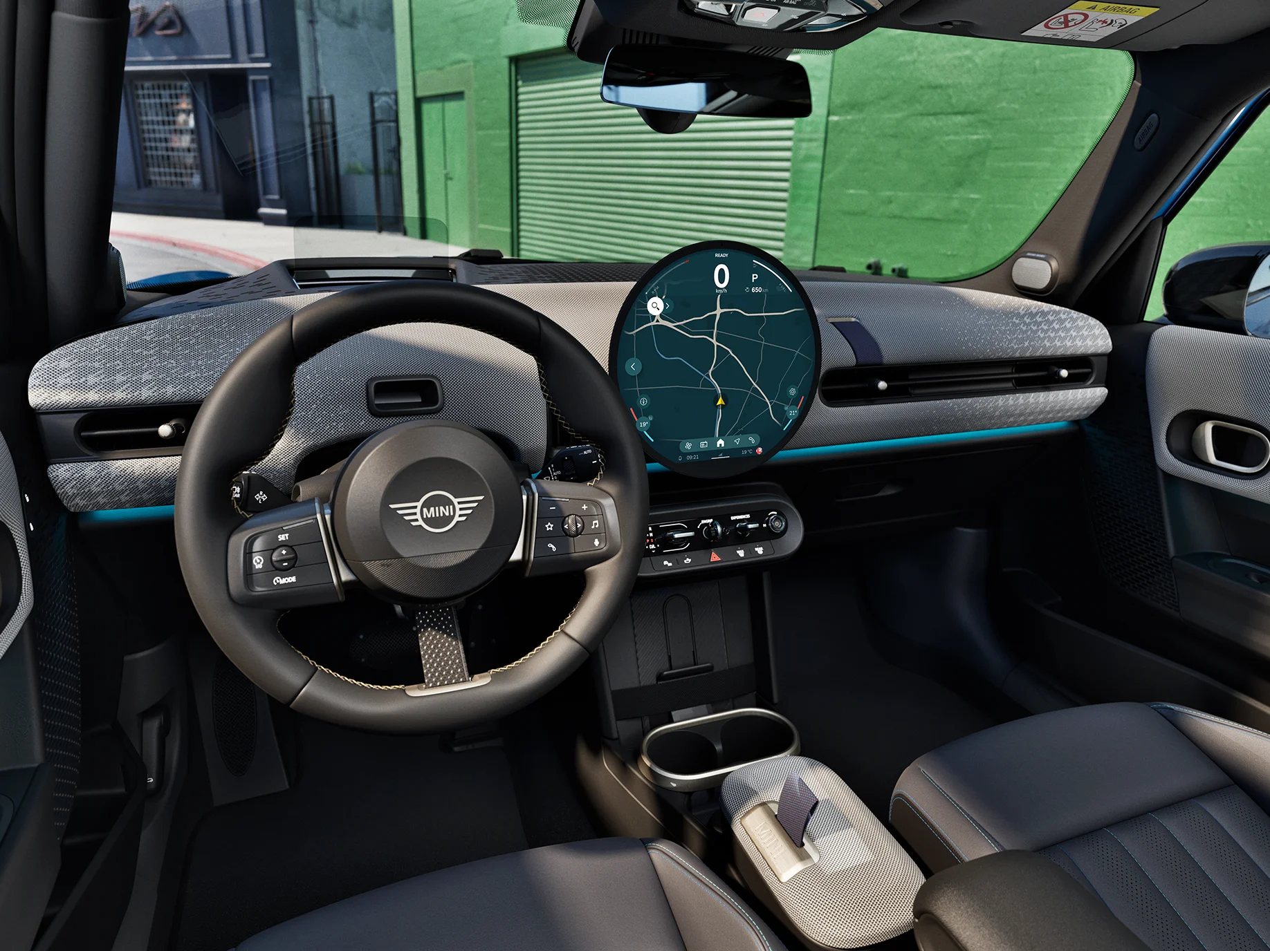 Innvendig visning av MINI Cooper 5-dørs med fokus på rattet, dashbordet og Interaction Unit.