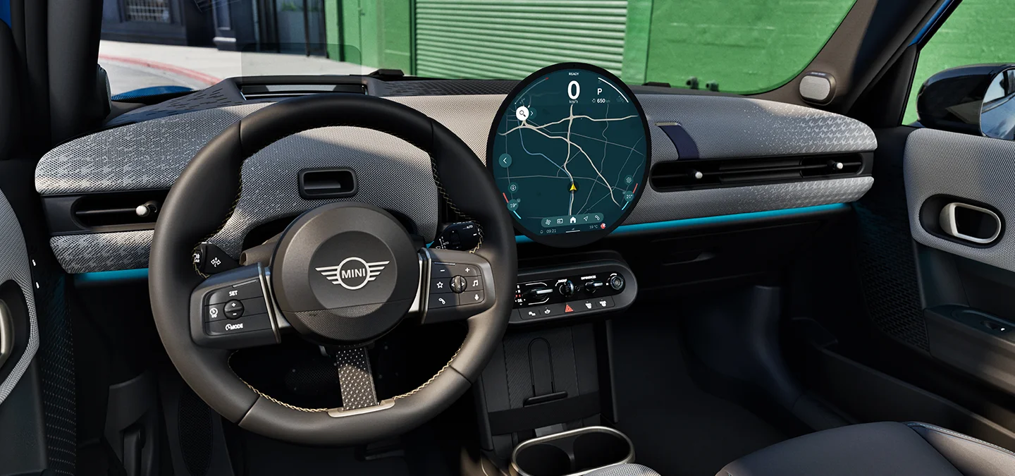 Innvendig visning av MINI Cooper 5-dørs med fokus på rattet, dashbordet og Interaction Unit.