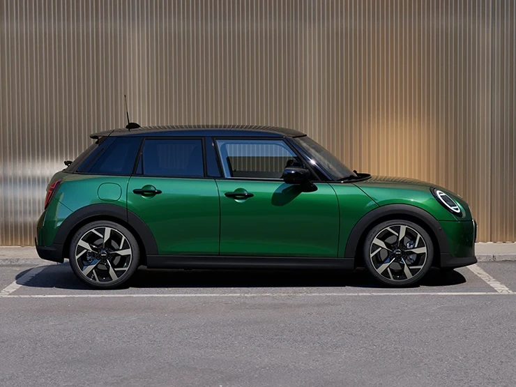 MINI Cooper 5-dørs i British Racing Green med tak i Black som parkerer, sett fra siden.