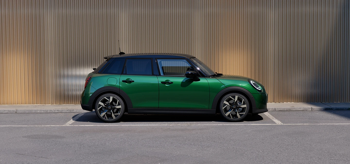 MINI Cooper 5-dørs i British Racing Green med tak i Black som parkerer, sett fra siden.