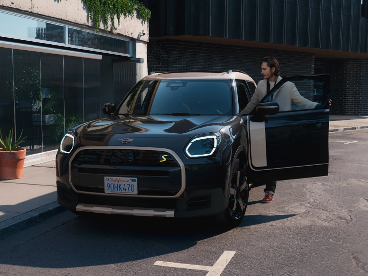 Den helelektriske MINI Countryman i Midnight Black med tak i Vibrant Silver i ei gate, sett forfra.