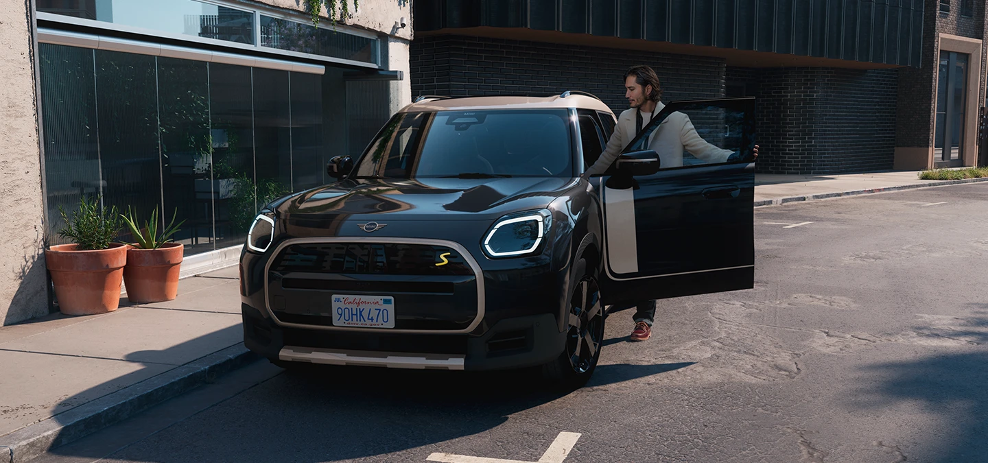 Den helelektriske MINI Countryman i Midnight Black med tak i Vibrant Silver i ei gate, sett forfra.
