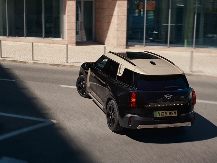 En parkert helelektrisk MINI Countryman i Midnight Black med tak i Vibrant Silver, sett ovenfra,