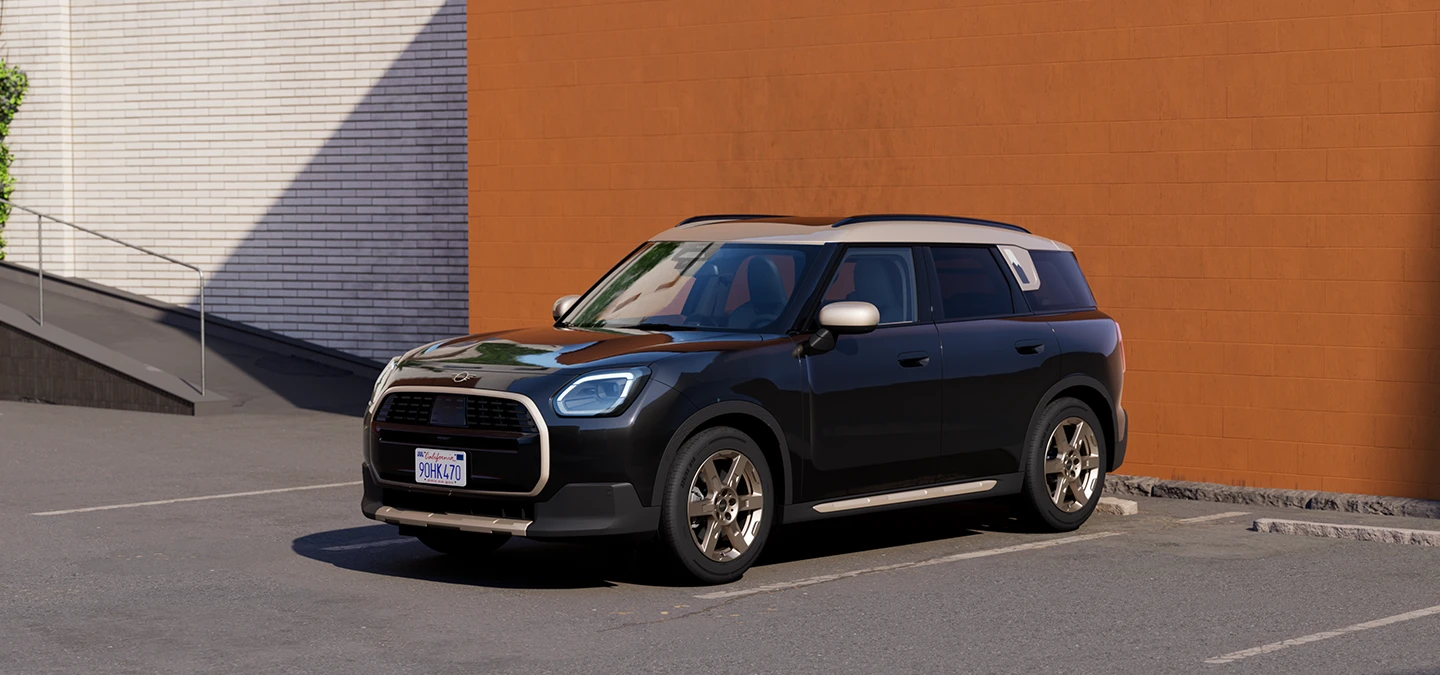 MINI Countryman i Midnight Black med tak i Vibrant Silver som parkerer, sett forfra og fra siden.