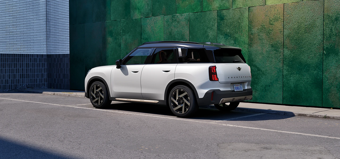 MINI Countryman i Nanuq White med svart tak som står i ei gate, sett fra siden.