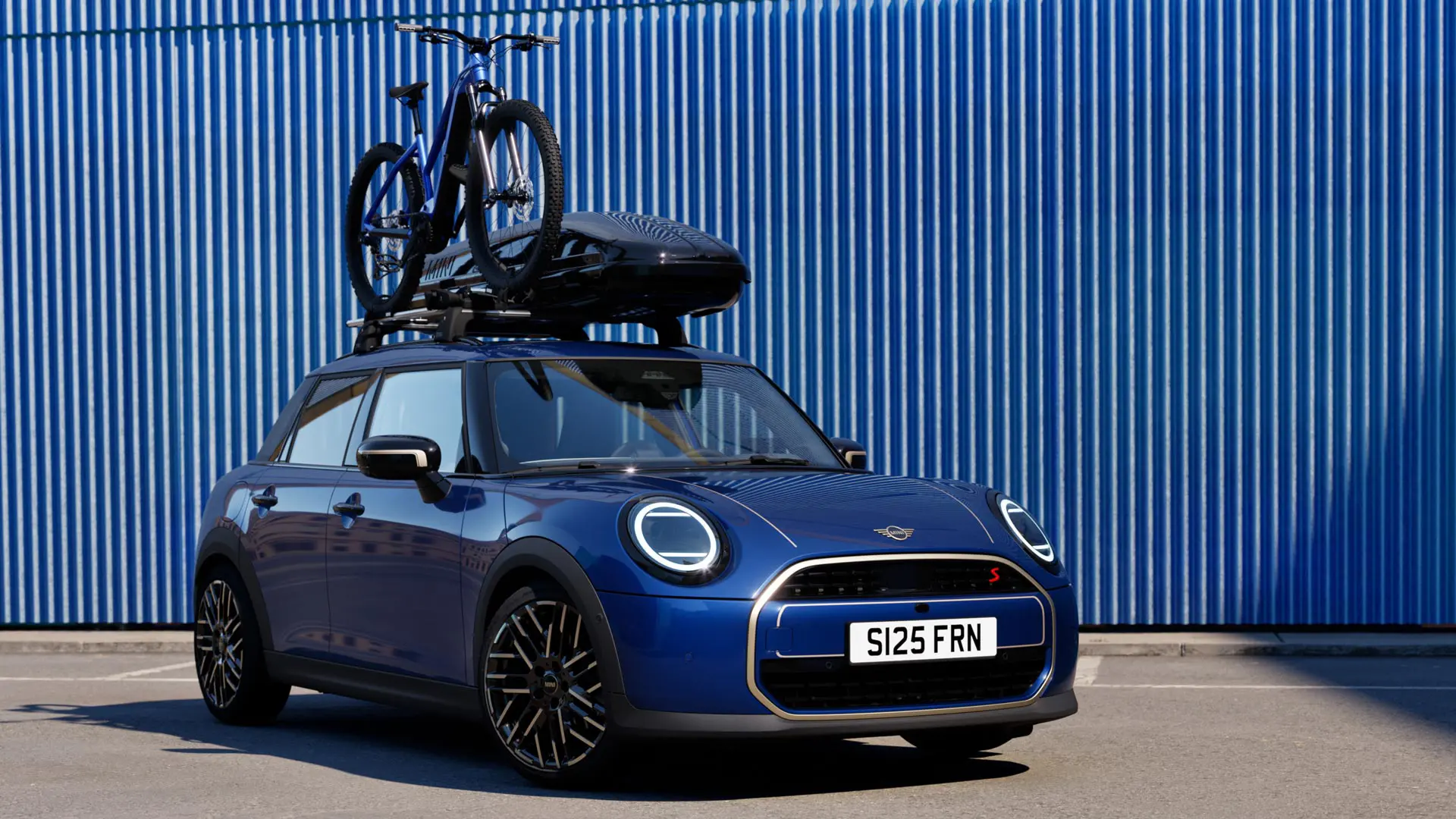 MINI Aceman i Indigo Sunset blå med MINI taksykkelstativ med terrengsykkel og MINI takboks 320 sett forfra.