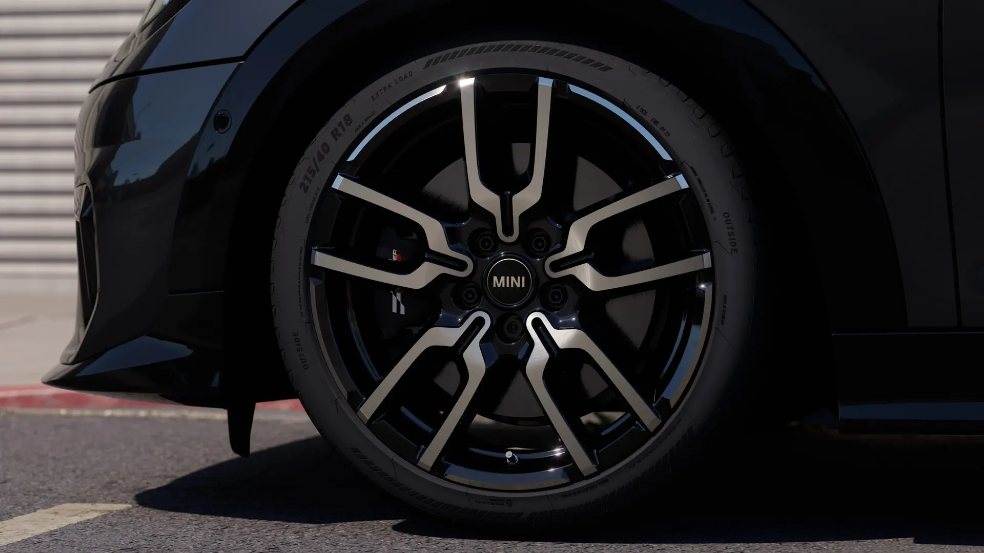 Nærbilde av JCW Lap eiker lettmetallfelg som viser sin særegne åpne eikedesignstruktur i Jet Black-finish.