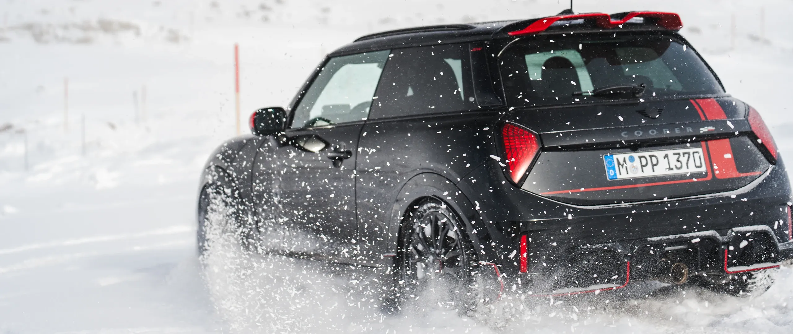 MINI Cooper JCW kjører gjennom snøen, sett bakfra.
