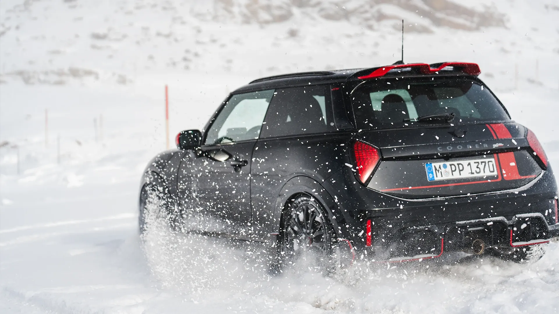 MINI Cooper JCW kjører gjennom snøen, sett bakfra.