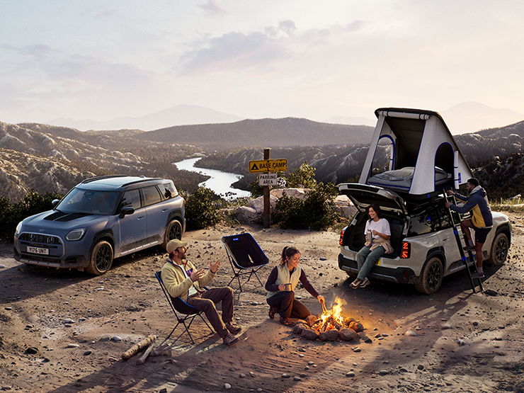 Bilde av to MINI Countryman Untamed Edition-kjøretøyer på et fjell i solnedgangen.