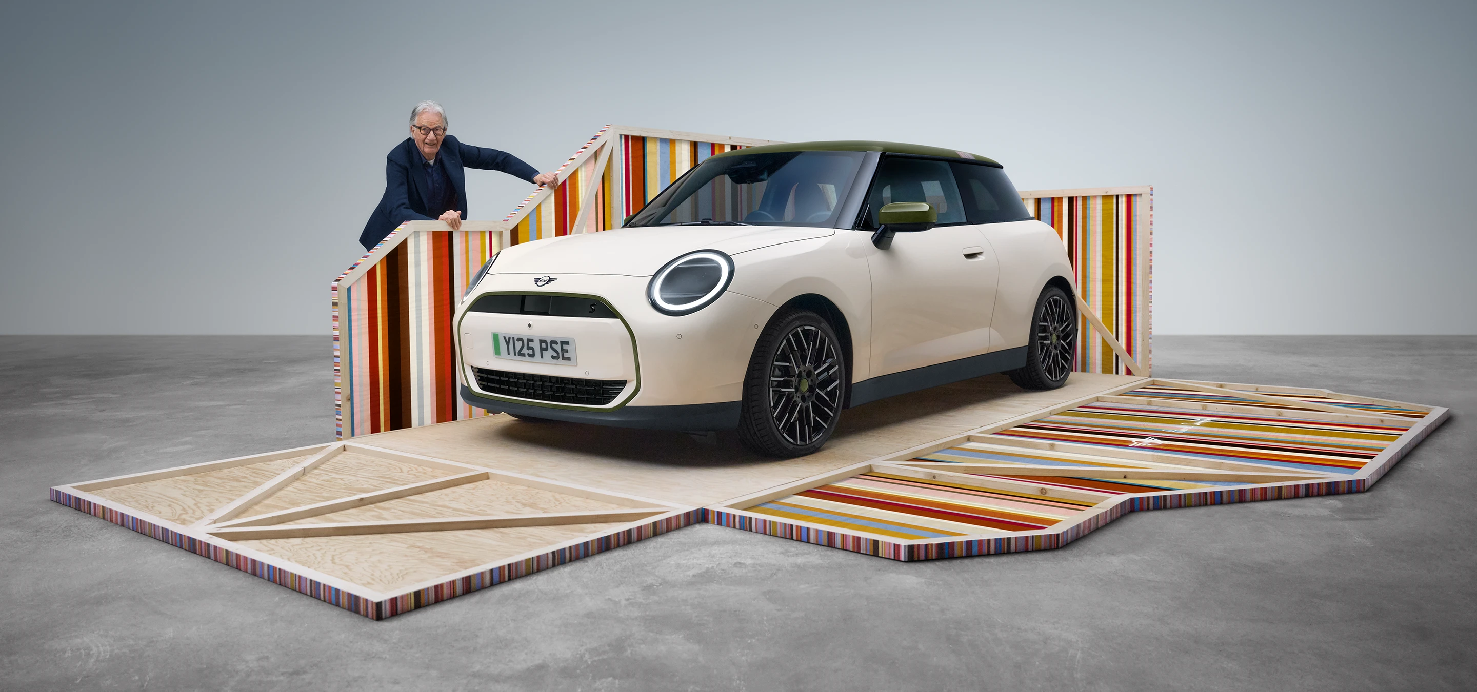 Helelektriske MINI Cooper Paul Smith Edition i Inspired White sett fra siden forfra med designer Paul Smith